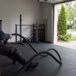 Person sitting on a bench doing upper-body cardio with battle ropes in a bright home gym