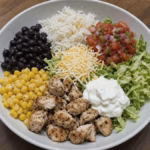 Copycat Chipotle chicken burrito bowl with rice, black beans, corn, shredded romaine, salsa and yogurt crema