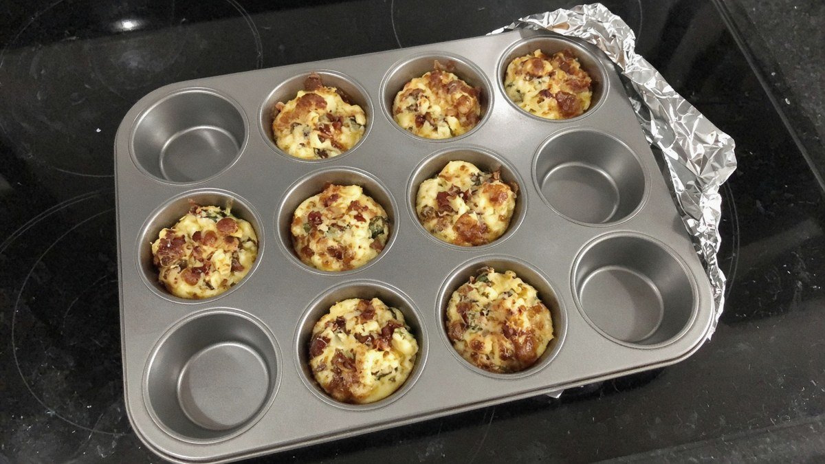 Muffin tin of baked copycat Starbucks egg bites with foil pulled back at one corner