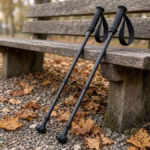 Pair of carbon Nordic walking poles with glove straps leaning on a wooden park bench