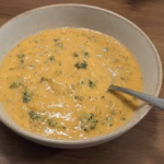 Bowl of high-protein copycat Panera broccoli cheddar soup with broccoli and a spoon