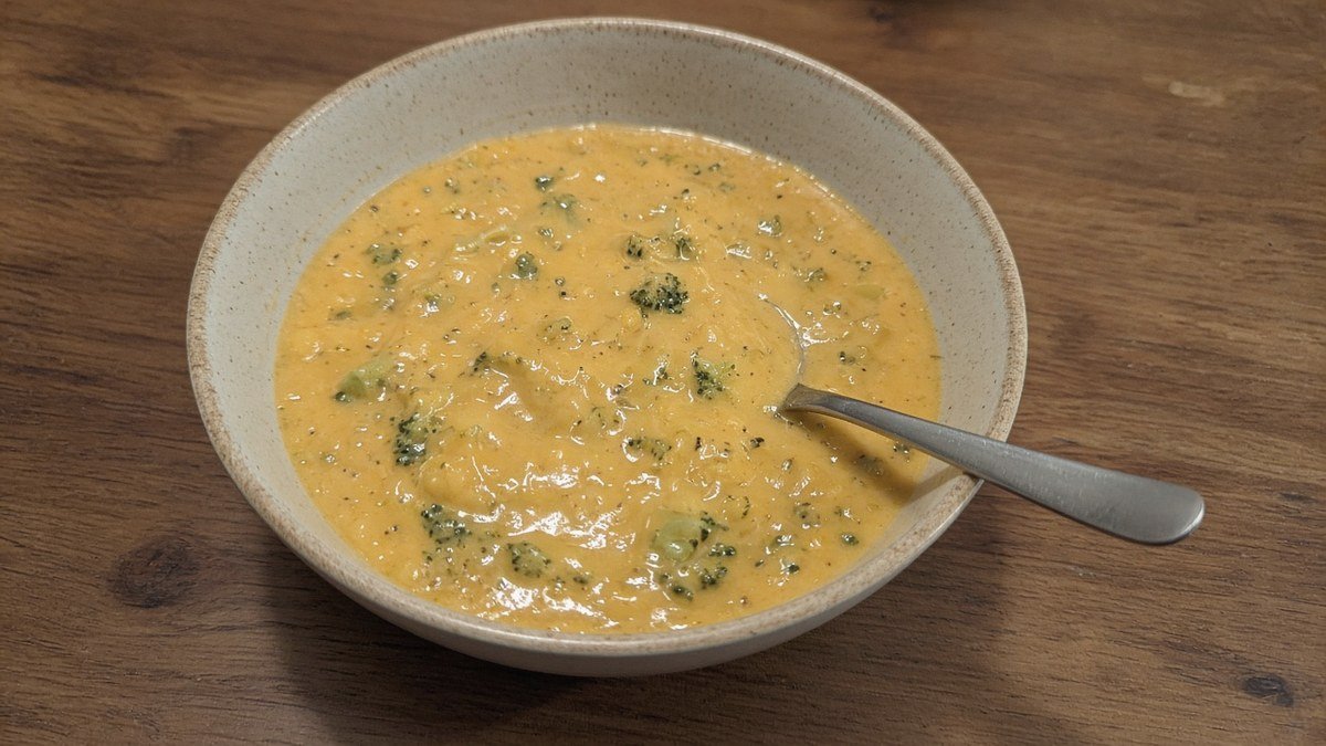 Bowl of high-protein copycat Panera broccoli cheddar soup with broccoli and a spoon