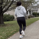 Woman walking briskly on a sidewalk to add daily steps and lose a pound